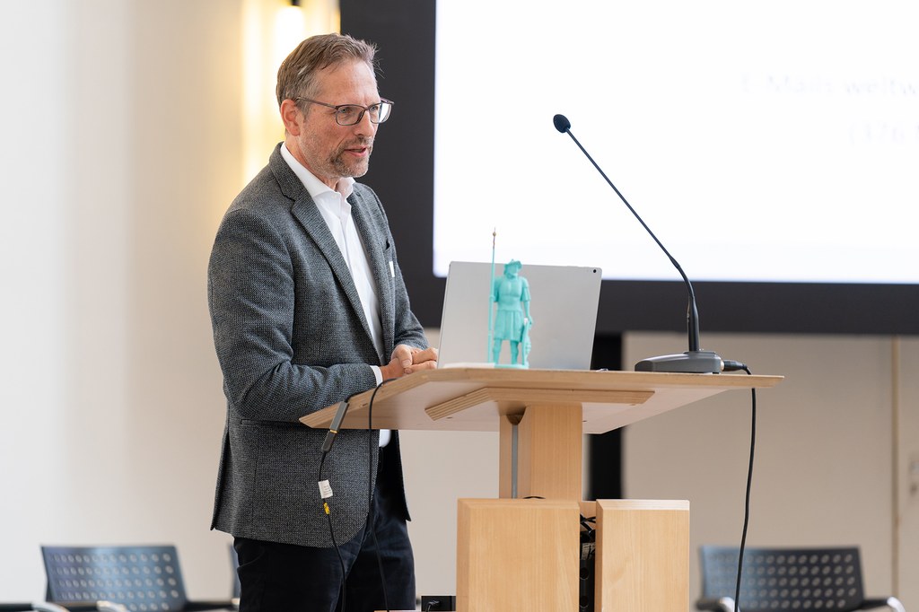 neusser-zukunftskongress-2022_08b.jpg Prof. Linus Schleupner von der Rheinischen Fachhochschule steht am Pult und hält einen Vortrag.